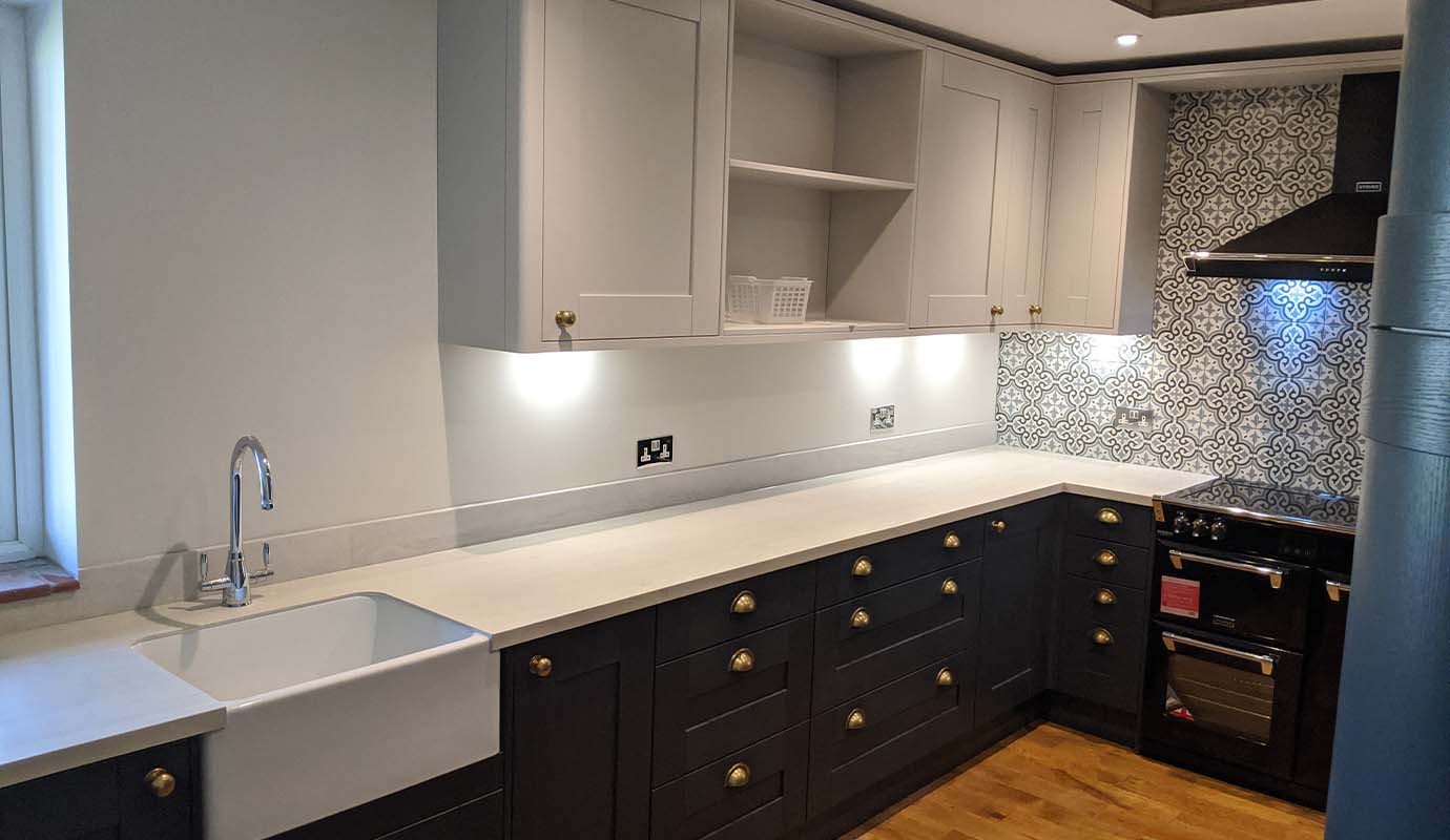 Modern kitchen with white cabinets, patterned backsplash, and wooden floor.
