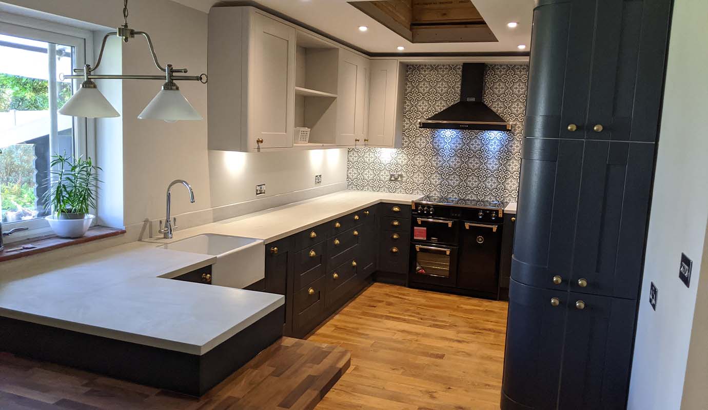 Picture of a kitchen with grey cabinets, white countertops, a patterned backsplash, and a wooden floor.