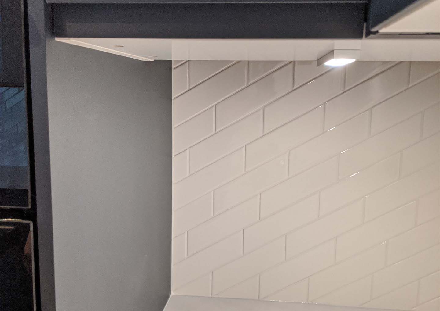 Interior corner showing white tiles and overhead cabinet.