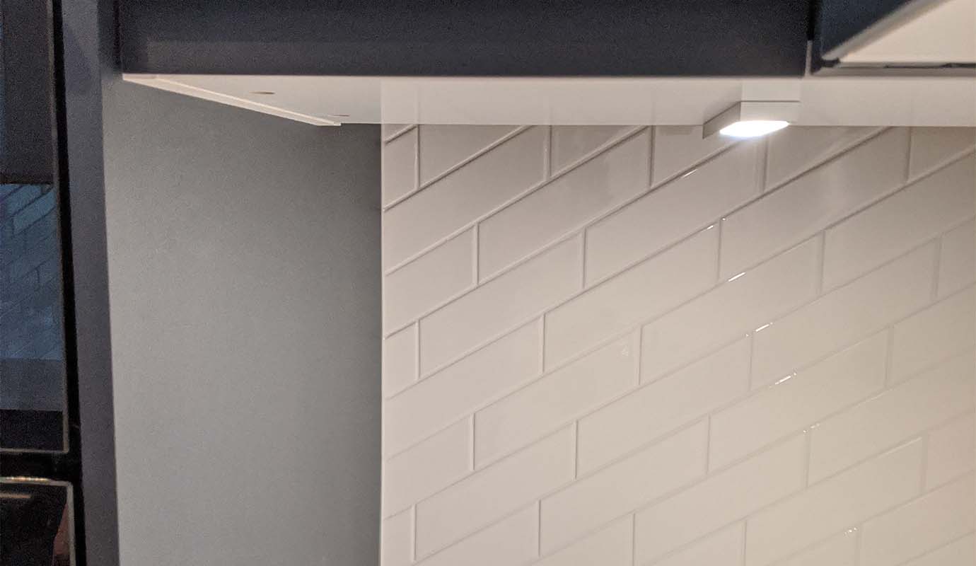 Interior corner showing white tiles and overhead cabinet.
