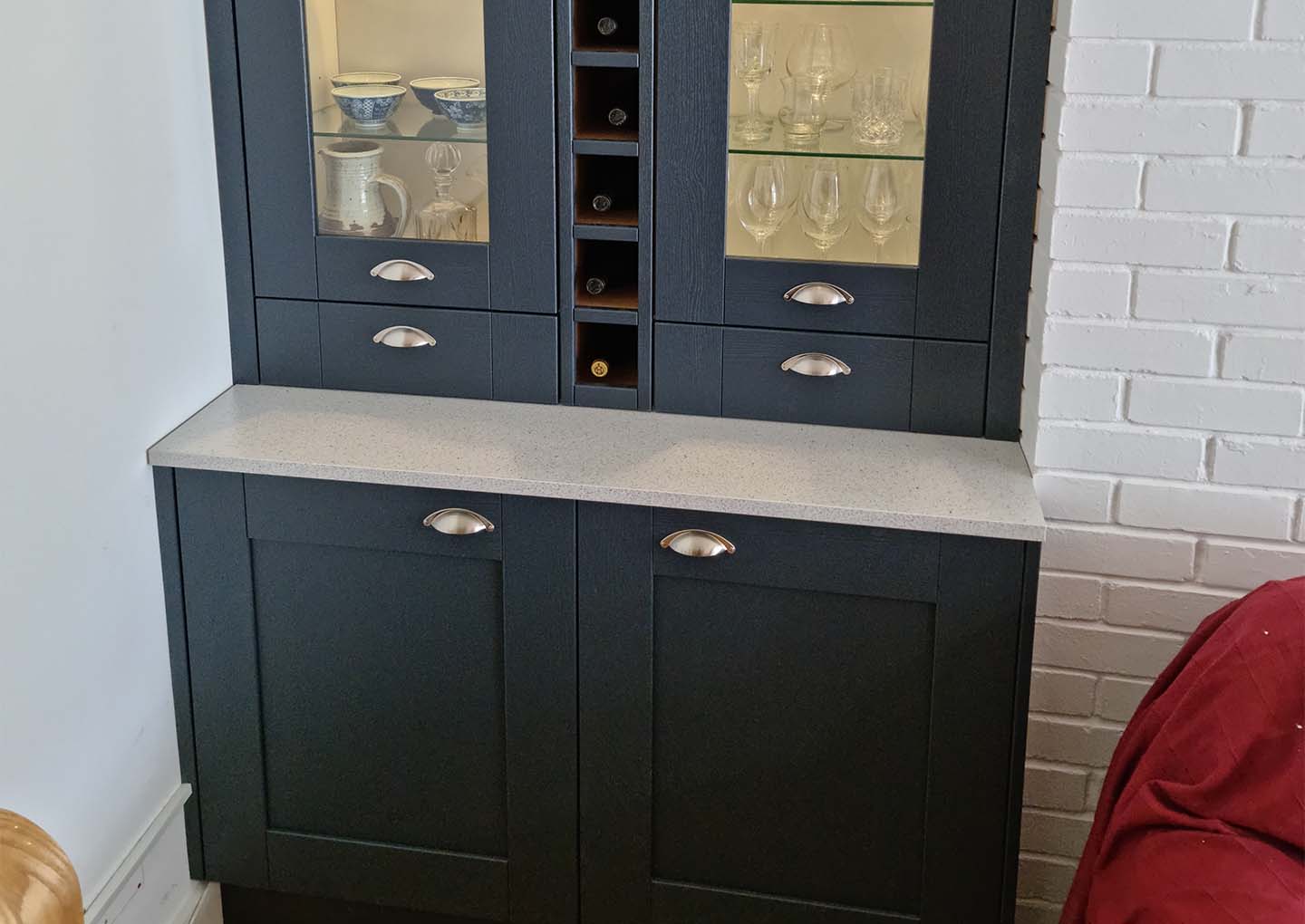 A black cabinet with glass doors displaying glassware