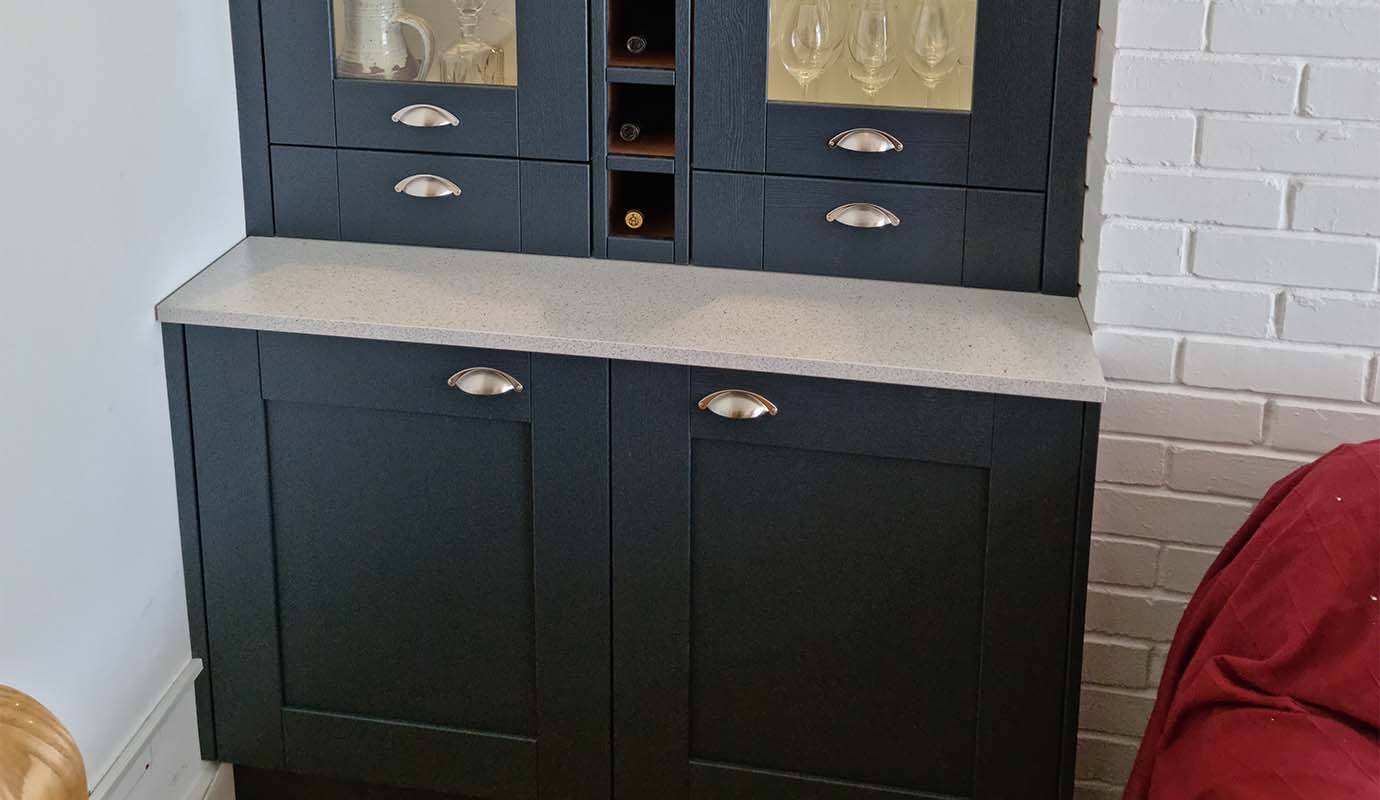 A black cabinet with glass doors displaying glassware