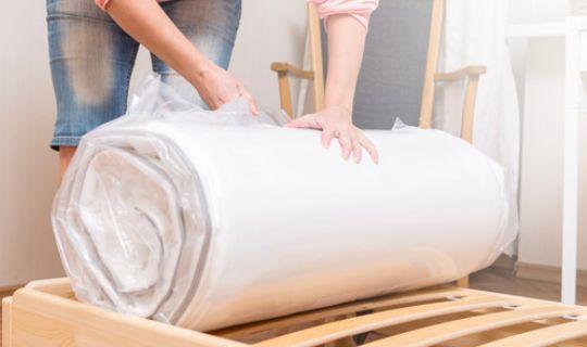 a woman unwrapping a brand new mattress on a bed frame