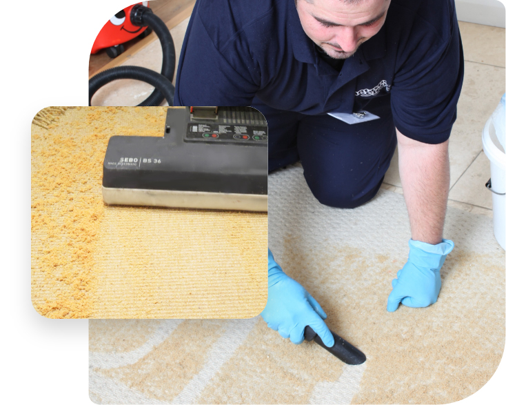 The image shows a Fantastic Services carpet cleaning technician wearing a dark blue uniform. He is kneeling down over a delicate area rug. The pile of the rug is covered with a dry cleaning powder. The technician is using a vacuum cleaner to remove the dry cleaning powder from the rug after it has been worked into the pile with a machine with rotating brushes.