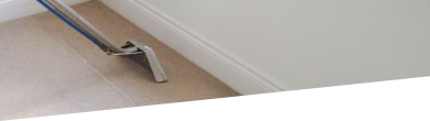 Professional carpet cleaner using hot water extraction equipment on a carpet in a London home