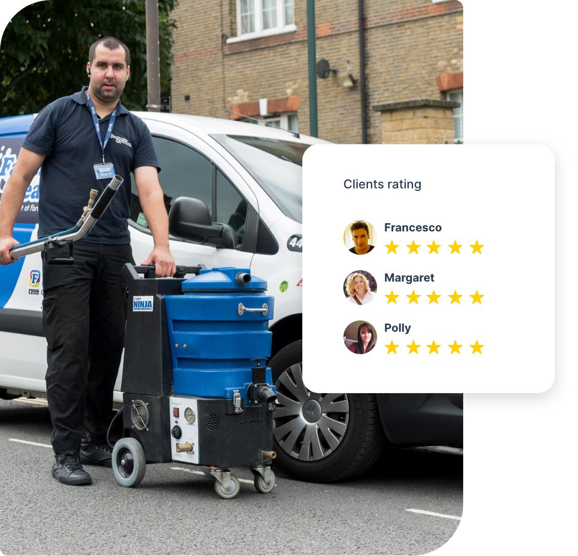 The image shows a Fantastic Services carpet cleaning technician who is standing in front of his work car. He is wearing a dark blue branded t-shirt and a badge around his neck. Next to him, there is a professional hot water extraction machine. The technician is holding the cleaning wand of the machine. He appears very competent and eager to clean some carpets and rugs to perfection.