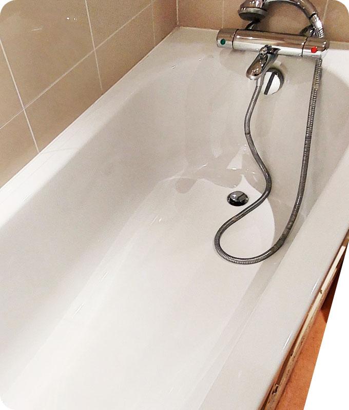 An image of a freshly cleaned bathtub gleaming with cleanliness. The tub's surface is sparkling and free from any dirt or grime, reflecting light to reveal its pristine condition. The drain is clear and the walls and floor surrounding the tub are free from watermarks. The bathtub appears inviting and ready for a relaxing bath.