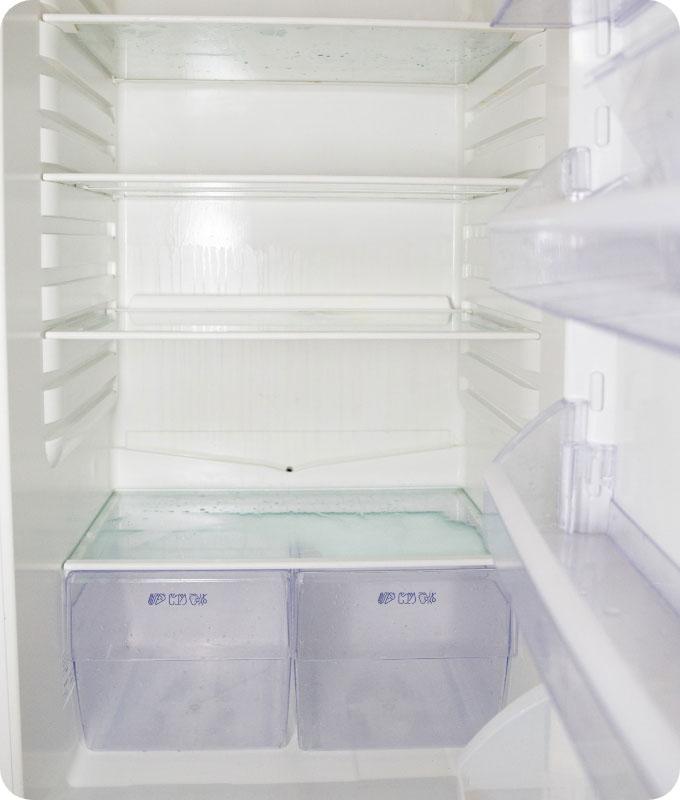 An image of the inside of a fridge after a thorough cleaning, looking fresh and immaculate. The shelves, drawers, and walls of the fridge are spotless, free from any dirt, food residue, or stains. The interior shines with cleanliness, and no traces of mold or mildew are visible. The fridge appears well-organized, with neatly arranged food items, and exudes a clean and hygienic feel. It is ready to store fresh food and maintain optimal food safety.