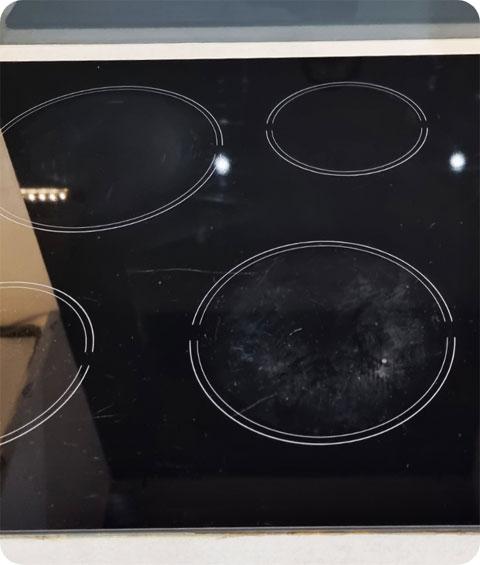 An image of a freshly cleaned black ceramic stove top, shining with cleanliness. The surface is free from any burnt food residue or greasy stains, revealing a smooth and glossy appearance. The burners and knobs are spotless, and the entire stove top has a polished and well-maintained look. It appears as good as new, ready for cooking delicious meals.