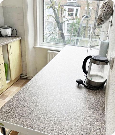 An image of a pristine and well-organized kitchen countertop after decluttering and cleaning. The countertop is clear of any items, and all appliances, cutting boards, and kitchen items are neatly arranged. The surface is sparkling clean, free from any spills, stains, or debris. The countertop exudes a sense of cleanliness and order, with a visually pleasing appearance.