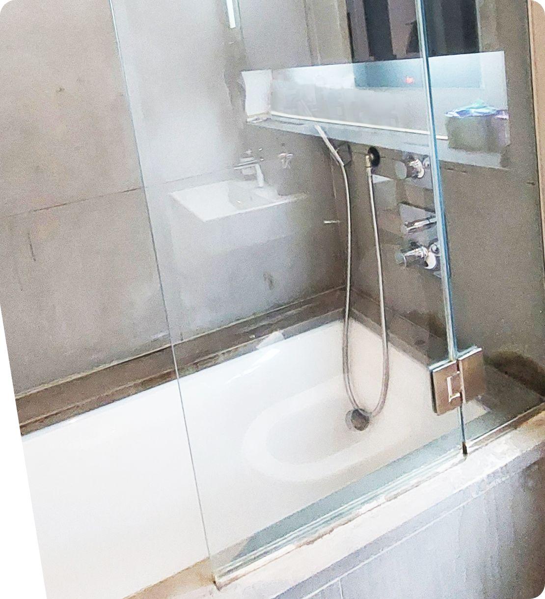 The image shows the same bathtub shower cabin but has been thoroughly cleaned. The glass door is now perfectly shiny and transparent. All the smudges and dried-up soapy scum are gone.