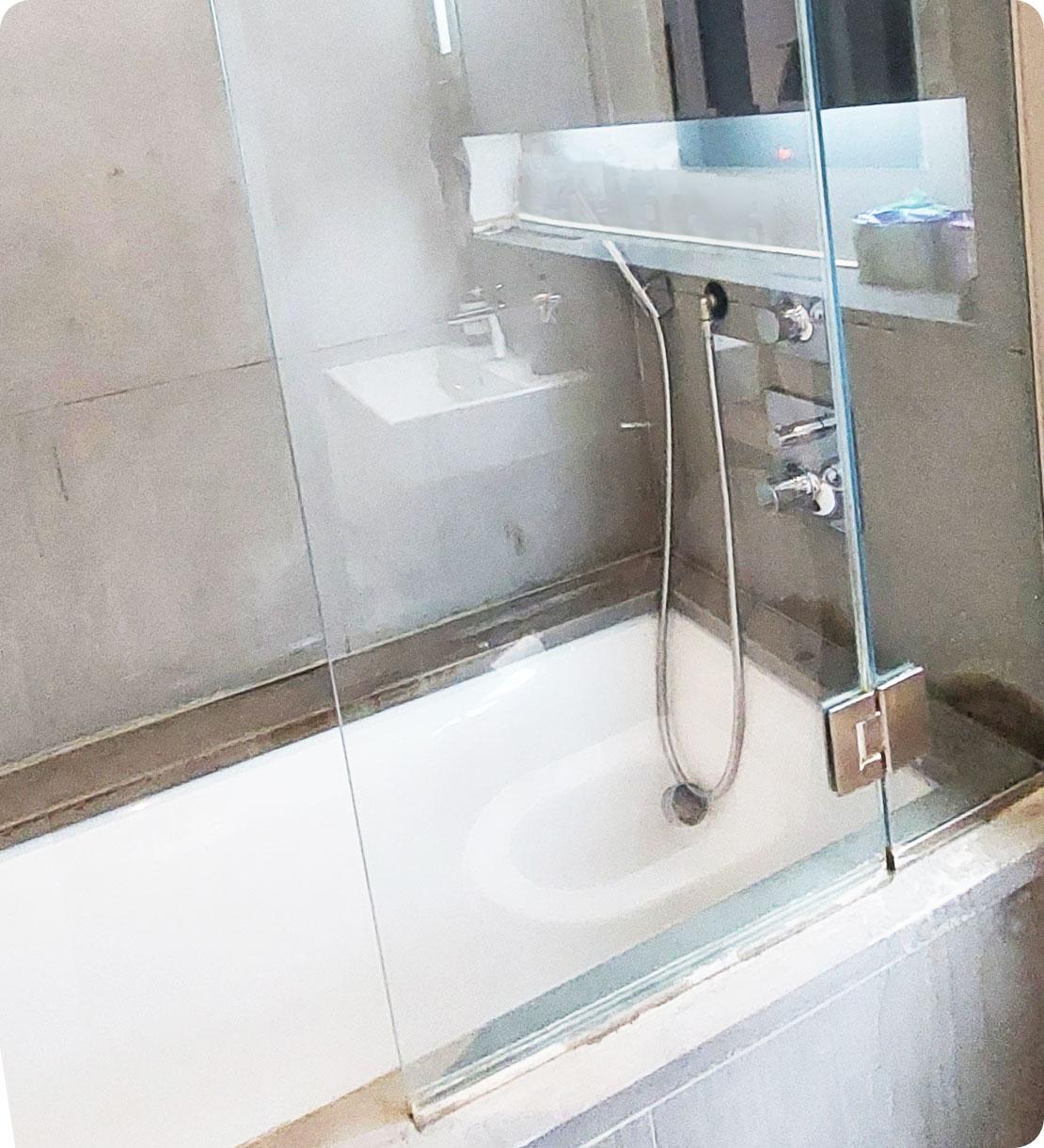 The image shows the same bathtub shower cabin but has been thoroughly cleaned. The glass door is now perfectly shiny and transparent. All the smudges and dried-up soapy scum are gone.