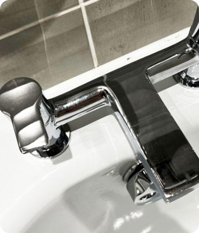 An image of a gleaming chrome bathroom faucet, sparkling with cleanliness. The chrome finish shines with a polished and lustrous appearance, free from any grime, hard water stains, or soap residue. The faucet handles and spout are spotless, reflecting light and showcasing their pristine condition. The entire faucet appears well-maintained and refreshed, ready to add a touch of elegance to any bathroom.