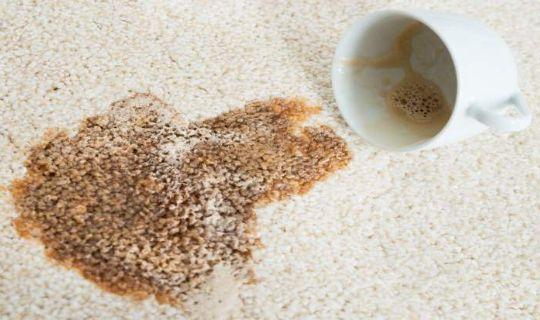 a coffee mug next to a coffee stain on a carpet