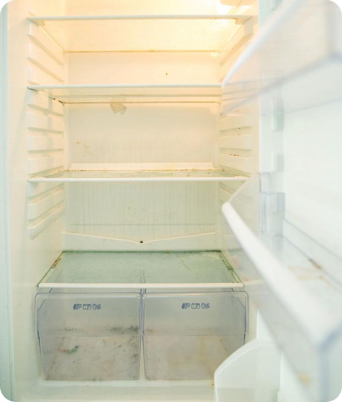 An image of the inside of a fridge covered in dirt, food spills, and stains. The shelves, drawers, and walls of the fridge are coated with dried-on food residue and sticky spills. Mold and mildew may be visible in some areas, and the overall interior appears neglected and unclean. The fridge looks in need of a thorough cleaning to restore its freshness and hygiene.