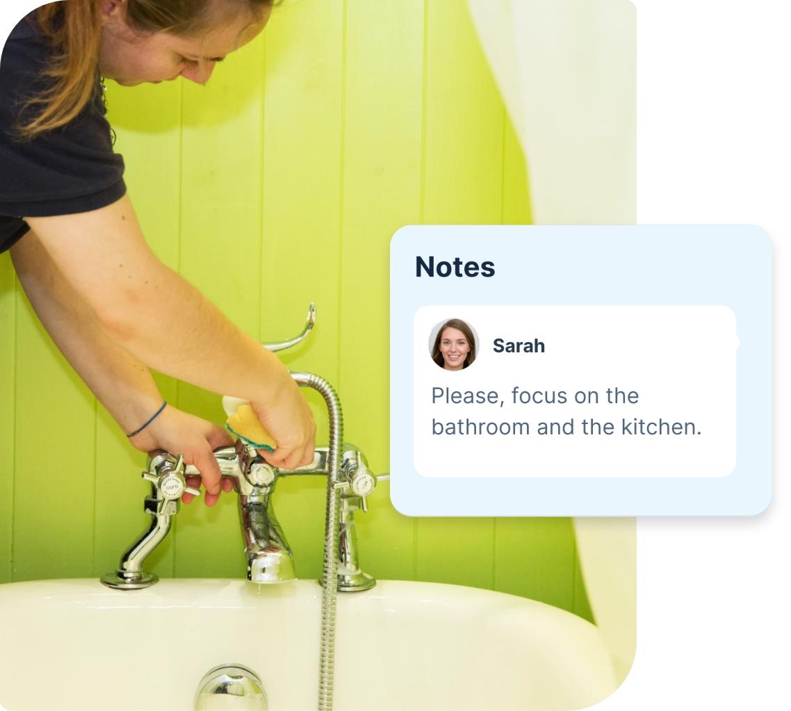 A domestic cleaner wearing a dark blue Fantastic Services uniform is shown in a domestic bathroom. She is standing over a white bathtub and using a sponge to clean the chrome tub faucet. Both the tub and the green tiled wall behind it appear perfectly clean and shiny. There is a segment which has been edited into the photo, showing a note from a customer. The note says “ please focus on the bathroom and the kitchen.”