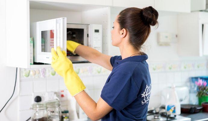 A regular cleaner in uniform who polishes a furniture.