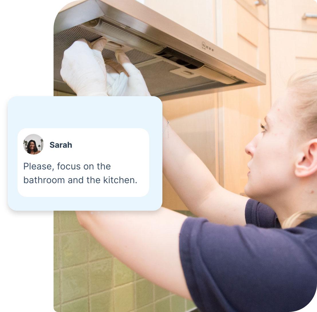 A Fantastic Services cleaner who is wearing a dark blue uniform and white latex gloves. She is standing in front of a domestic kitchen range hood and adjusting it. The photo is edited and includes a segment showing a note from a customer. The note says “Please focus on the bathroom and the kitchen.”