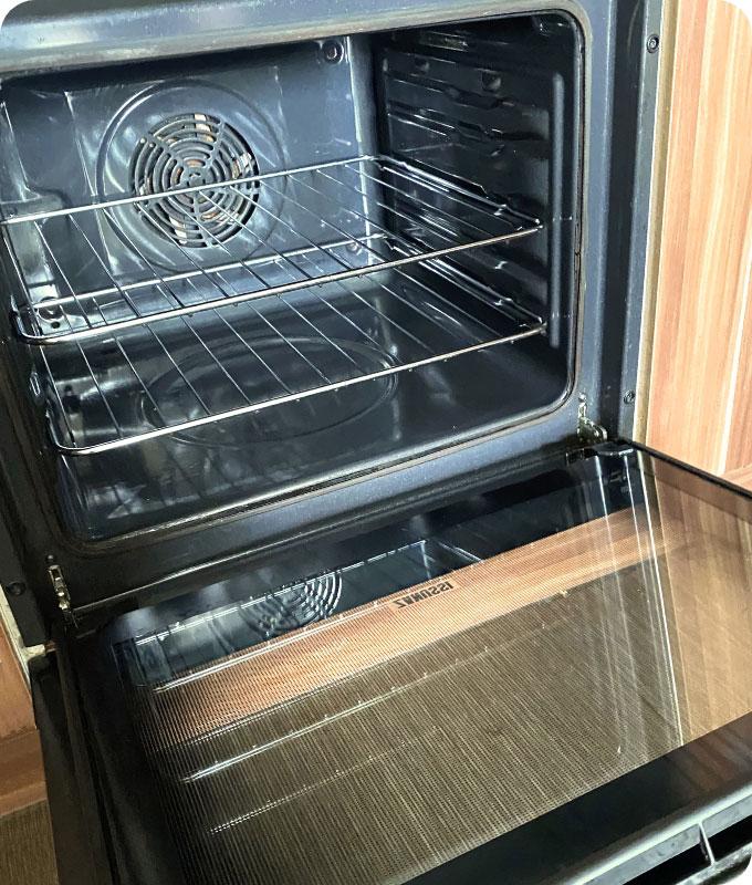 An image of a sparkling clean oven after professional cleaning. The oven interior is spotless, with no grease or grime, and the oven racks are gleaming. The oven door is transparent, showcasing the immaculate interior, indicating attention to detail during the cleaning process. The oven looks fresh, inviting, and ready to be used for cooking delicious meals.