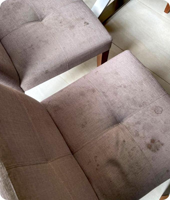 Grey dining chairs that have many set-in stains.