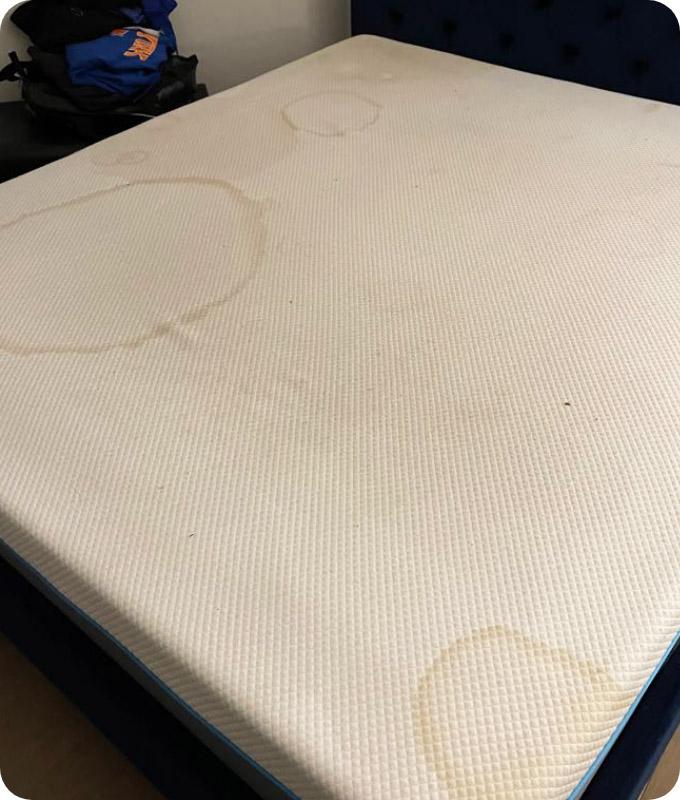 A white mattress that has two very unsightly yellowish stains.