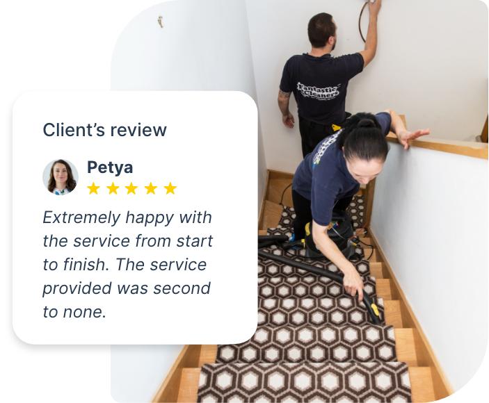 The image shows a couple of Fantastic Services tenancy cleaners who are on the job. They are cleaning a carpeted stairway. One of the cleaners is hoovering the carpeted area while the other is removing smudges from the wall.