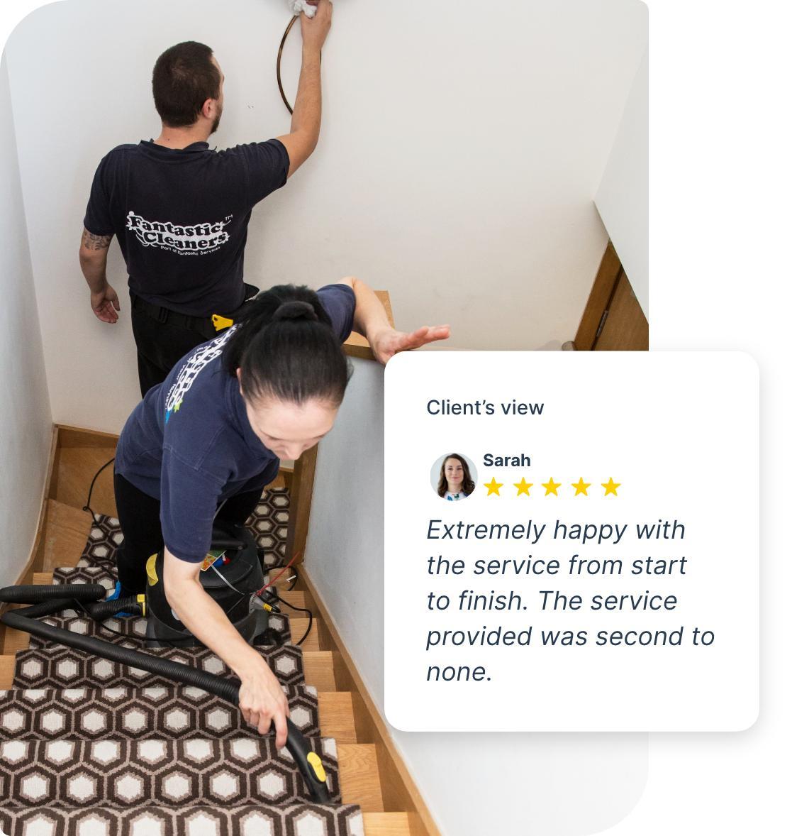 The image shows a couple of Fantastic Services tenancy cleaners who are on the job. They are cleaning a carpeted stairway. One of the cleaners is hoovering the carpeted area while the other is removing smudges from the wall.
