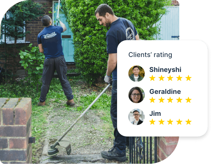 The image shows a couple of gardeners who are working in the front yard of a house. One of them is removing weeds from a walkway, the other is trimming a shrub.