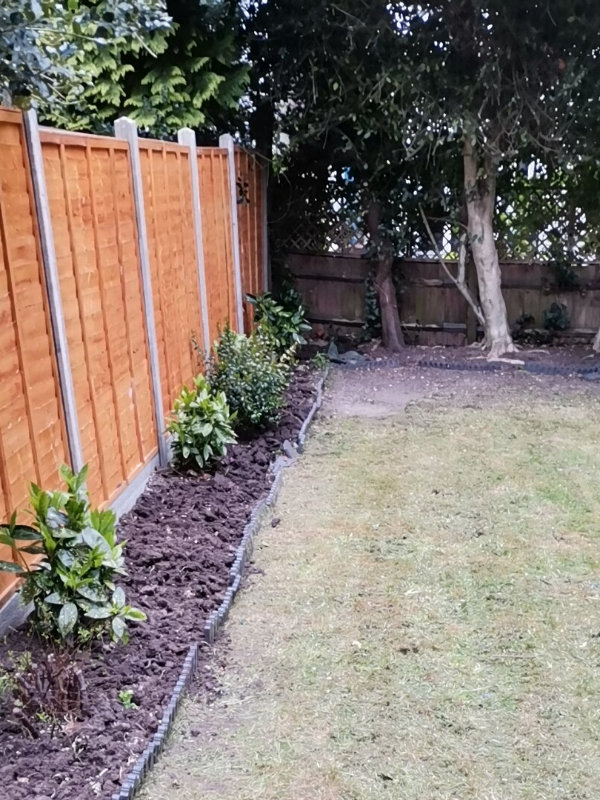 Cleared and neatly trimmed garden with tidy lawn and pruned hedges after professional service
