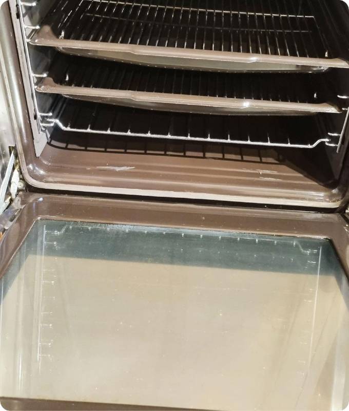 The image shows the same open oven after deep cleaning. The interior looks shiny and polished, the oven glass has been thoroughly cleaned.
