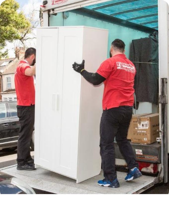 The image shows two Fantastic Services movers who are loading the back of a truck with furniture.