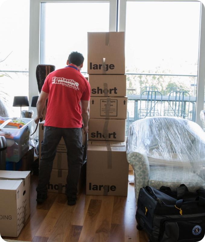 The image shows a Fantastic Services mover who is packing belongings in a living room.