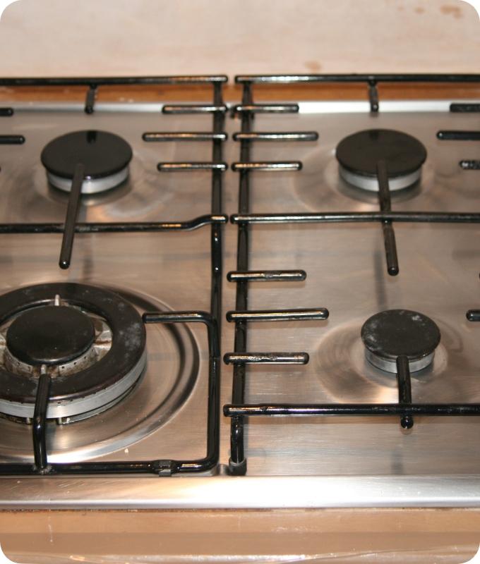 The image shows the gas stove after it has been cleaned. The contrast is stark, the stove is now shiny, and it almost looks like it has never been used.