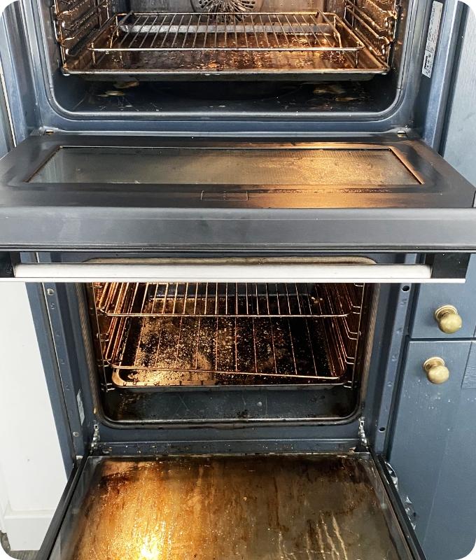 The image shows a front shot of a double oven with oven chambers stacked. The oven chambers appear to be highly neglected and dirty, caked with greasy splatters and food stains.
