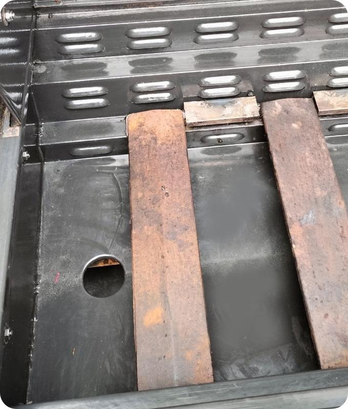 The image shows the same bottom of a grill after professional cleaning. It appears clean and polished.