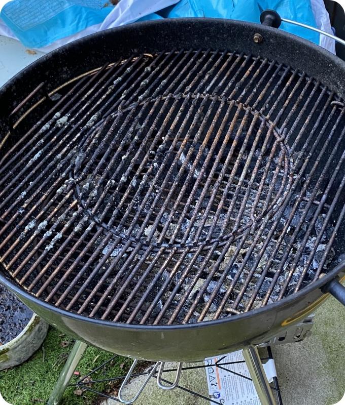 The image shows a round-shaped barbeque that is quite filthy.