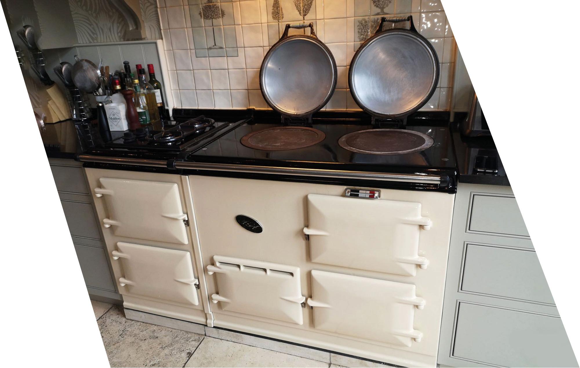 The image shows a white AGA kitchen range that has been professionally cleaned. It looks shiny and polished, almost like brand new.
