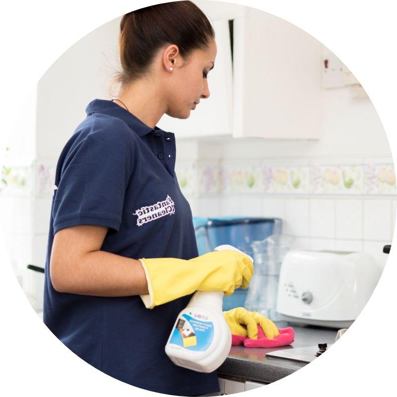 Deep Cleaners in Welwyn Garden City Book Top Rated Services. A cleaner in yellow gloves wiping a microwave with a red cloth, maintaining a spotless kitchen.