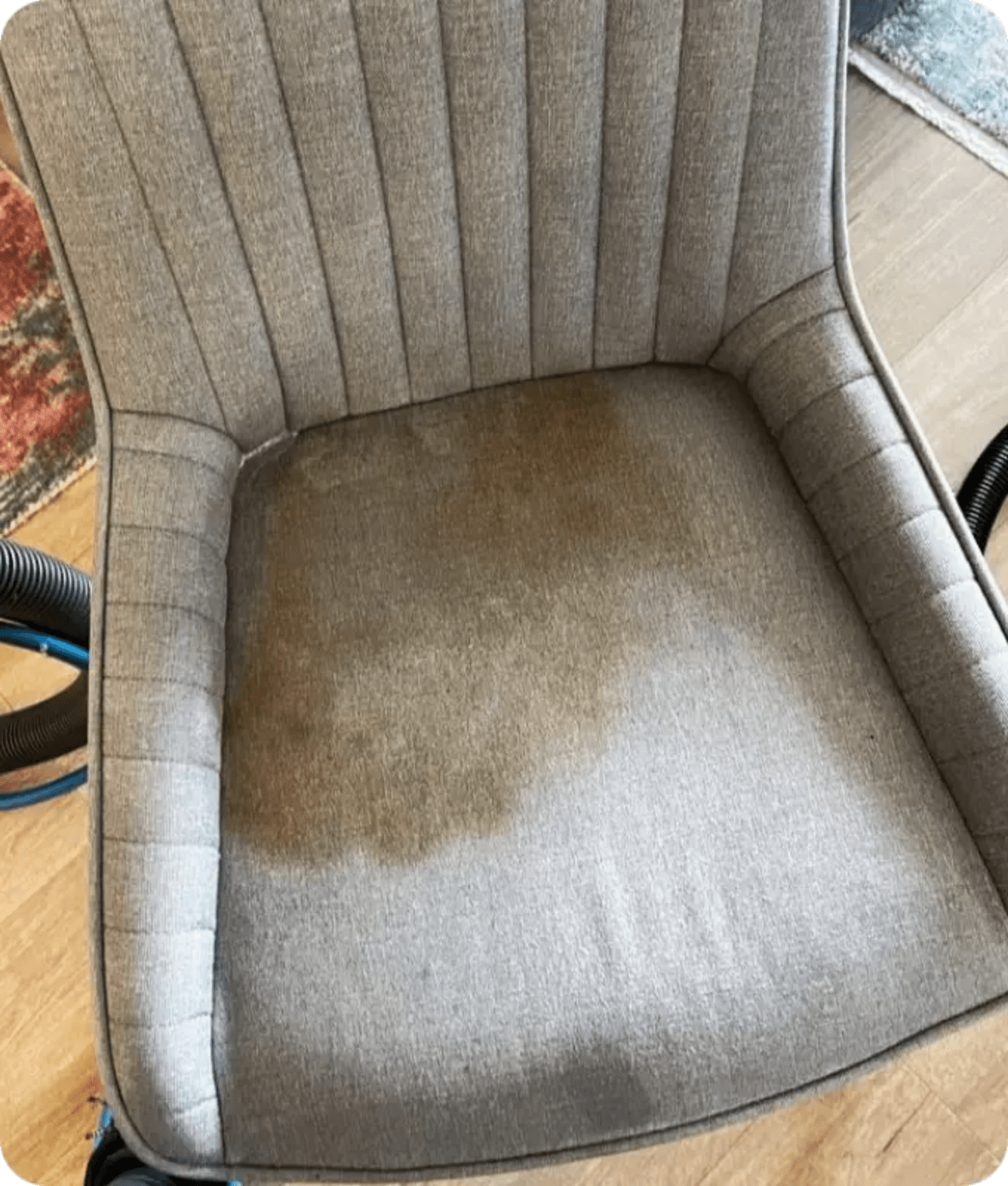 Close-up view of a grey upholstered chair with dark stains on it