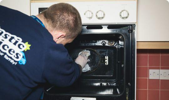 Professional in a dark uniform during an oven cleaning service